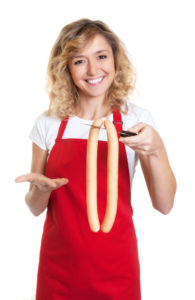 Lachende Wurstverkäuferin präsentiert frischen Wienern